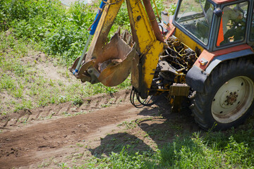 An excavator removes a large rock from a green agricultural field, preparing the land for planting. © Александр Ланевский