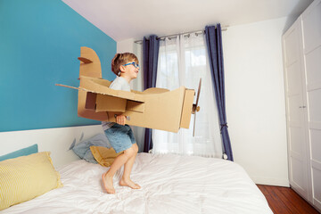 Little boy pretends to fly, holding a big cardboard airplane