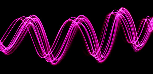 Light Painting Photography - swirly waves of neon pink purple light against a black background