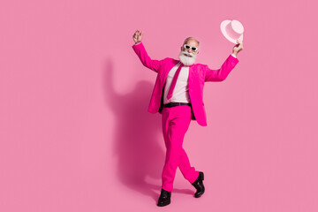 Full body photo of elderly white hair santa man dancing mc showman sunglass hold hat wear stylish pink suit isolated over pastel background