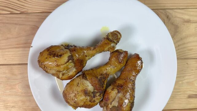 Baked chicken drumsticks on dish on rustic table, close-up