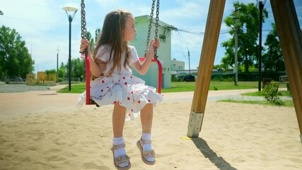 Little child girl swinging on swing enjoy childhood summer outdoor playground with positive emotion. Kid flying playing cheerful activity excitement enjoy freedom