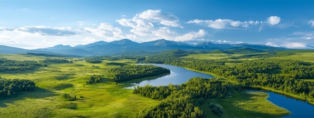 Fototapeta premium A bird's-eye perspective of a serene lake encircled by verdant hills and a distant mountain range, crowned with clouds in the sky