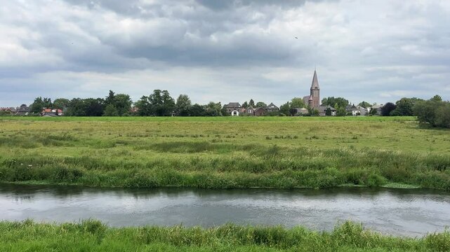 The church tower of Ottersum and the Niers river in Summer. Village in the Dutch province of Limburg, municipality of Gennep in the Netherlands.
