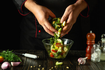 Cooking healthy vegetable salad in a bowl. Chef prepares a mix of chopped vegetables and aromatic spices. Service concept for a hotel or restaurant