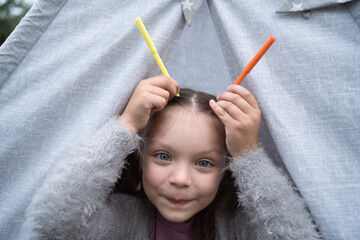Little girl put markers to her head pretending they were horns and laughing