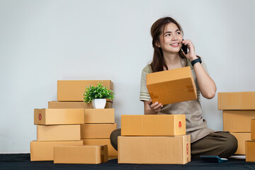 Young Business Owner Managing Startup Operations and Talking on Phone Surrounded by Cardboard Boxes