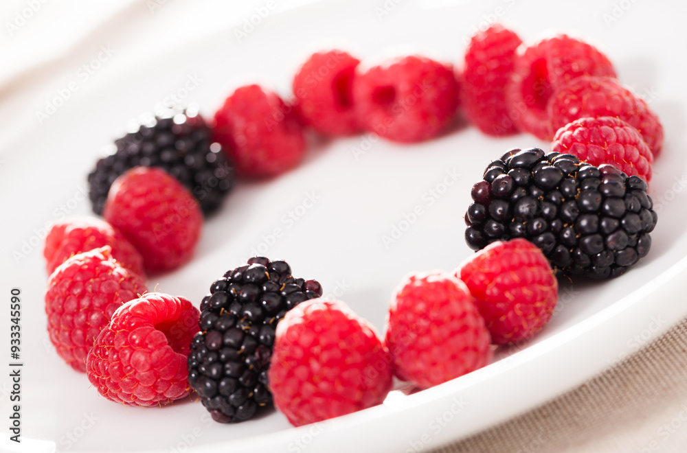 Wall mural Raspberries and blackberries laid out on a white plate in circle