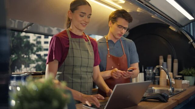 Portrait of a Couple of Small Business Owners Working in a Modern Street Food Cafe. Workers Preparing for a Busy Day, Operating a Delivery Software on a Laptop Computer and Preparing Orders