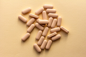 vitamins or supplements are scattered on a beige background top view