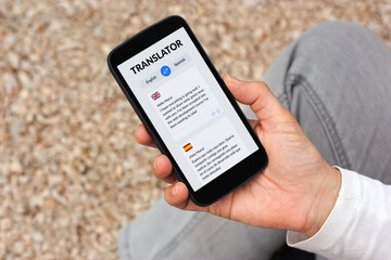 Hand holding smartphone with language translator app on screen. 