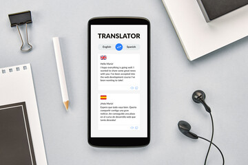 Overhead view of a smartphone on a desk with a language translator app open on the screen.
