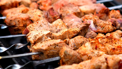 Close-up of sizzling kebabs on skewers grilling over an open flame. Perfect for showcasing outdoor cooking and barbecue flavors.