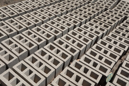 Rang&eacute;es de parpaings creux gris en ciment, form&eacute;s de trois alv&eacute;oles, et s&eacute;chant sur le sol. Mat&eacute;riaux de construction constitu&eacute;s de blocs align&eacute;s formant une surface rugueuse. Photo prise au S&eacute;n&eacute;gal.