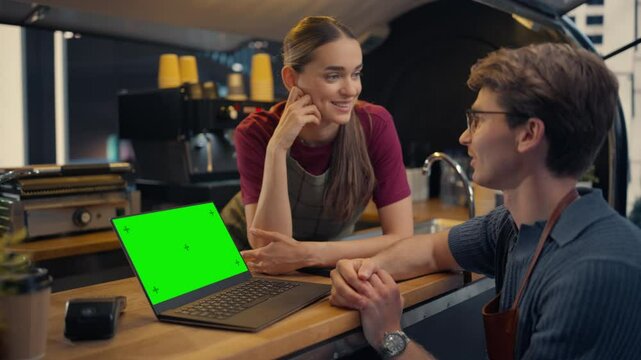 Street Cafe Manager and Female Barista Using Laptop Computer with Green Screen Mock Up Display at a Food and Coffee Truck, Discussing Business Strategies and Financial Reports