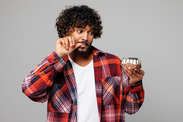 Young sad tempted dissatisfied Indian man he wears red shirt casual clothes hold in hand look at...