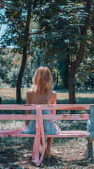 Woman Sitting on Pink Ribbon Bench in Park for Breast Cancer Awareness
