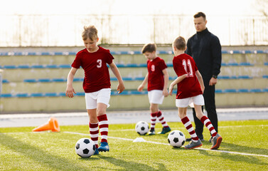 Obraz premium Soccer Education for Young Boys. Physical Education Class for School Children. Young Coach With Kids in Team on Training Unit. Youth Team Coach Training School Boys in Football Soccer