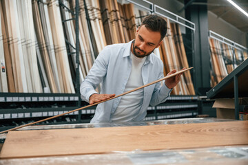 Quality of the wood in parquet, checking. Man is in the hardware shop