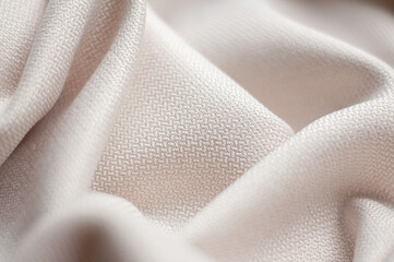 Folds of beige textured fabric. Beige background of fabric.