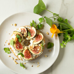bagel with ricotta and figs on white marble table, top view