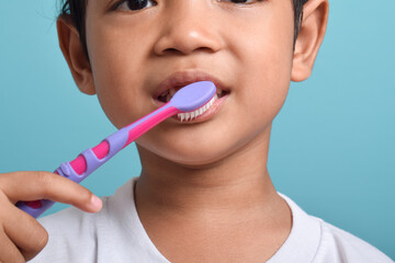 Close up happy Asian boy with clean teeth brushing his teeth isolated on blue background. Children's dental hygiene, Medical care