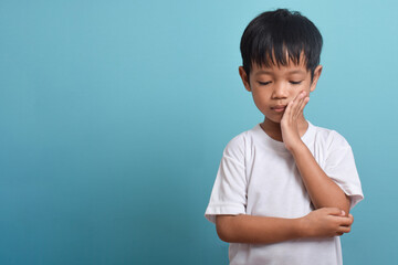 Little Asian boy suffering from toothache. toothache emotions large inflated cheek. A sad child with a toothache. Dental problem.