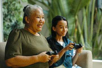 Grandma playing console with her grandchild during their leisure time at home