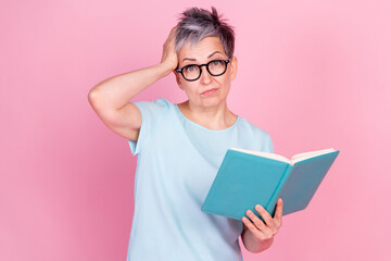 Portrait of nice aged lady hand touch head read book blue t-shirt isolated on pink color background