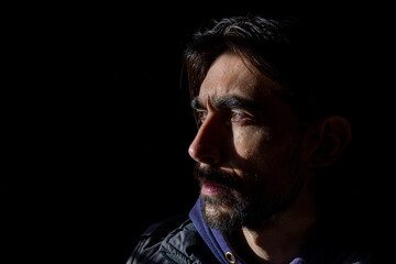 rostro lateral con mirada seria de hombre sobre fondo oscuro 