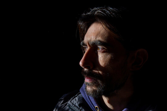 rostro lateral con mirada seria de hombre sobre fondo oscuro 
