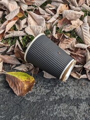 A discarded Coffee Cup and Lid with Liquid Waste Litter on Pavement