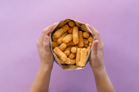 Children hands holding bamba in foil bag. Bamba is popular snack among children and adults in Israel. Its made of peanut butter flavoured puffed corn. Not sweet, rich in protein