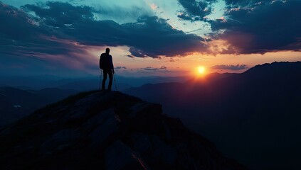 Fototapeta premium Silhouetted hiker on a mountaintop at sunset.