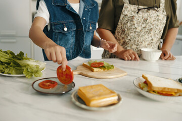 Close-up of family cooking sandwich with vegetables together in the kitchen