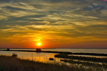 Amazing sunset over the lagoon: reflections on the water and strips of land with wild nature