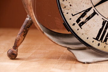 Broken old analog clock with glass and metal frame on wooden table, broken structure