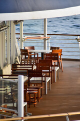 Outdoor seats on passenger ship deck with the calm seascape. Cruise ship deck. Wooden promenade deck on a luxury cruise liner. Ocean in background.