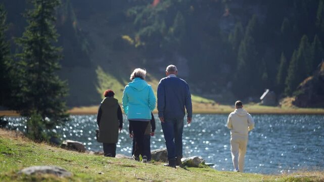 Retired People Walking by a Sparkling Lake as a Young Man Runs Past