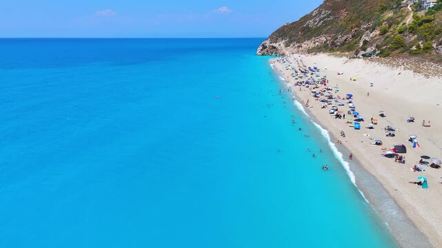 Aerial view of the secluded Milos beach with people having fun in the turquoise sea on the Ionian island of Lefkada, Greece