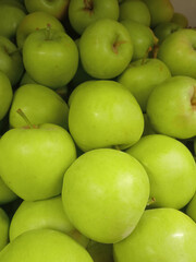 Green apples in the supermarket. There are a lot of green apples on the market. The concept is the benefits of green apples. Apple background. Organic fruits. Vegetarianism.