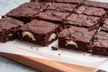 Chocolate brownie cake with cream cheese on wooden board, close up