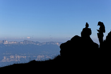 Silhouettes of hikers on the slopes of Belledonne mountain range in french alps