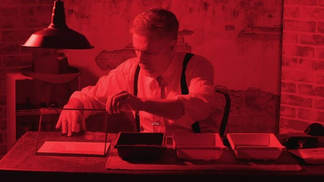 vintage man developing film under red safelight