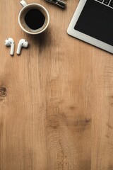 Fototapeta premium A minimalistic workspace with coffee, earphones, and a laptop on a wooden desk.