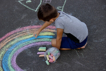 Naklejka premium the boy draws with chalk on the asphalt. Selective focus