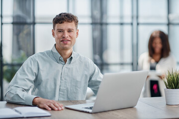 young man sitting in the office working at a laptop