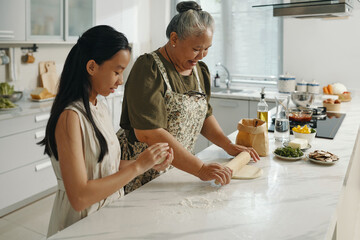 Granddaughter helping her grandma to bake in the kitchen