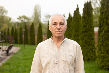 Senior man outside on sunny day in nature wearing Ukrainian embroidered shirt. Independence day of Ukraine