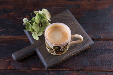 Espresso in a small ceramic mug on a wooden table